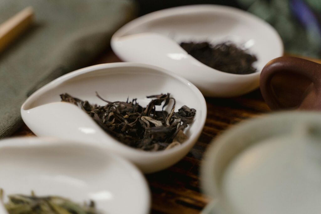 Porcelain dishes holding various loose tea leaves, highlighting traditional tea culture.